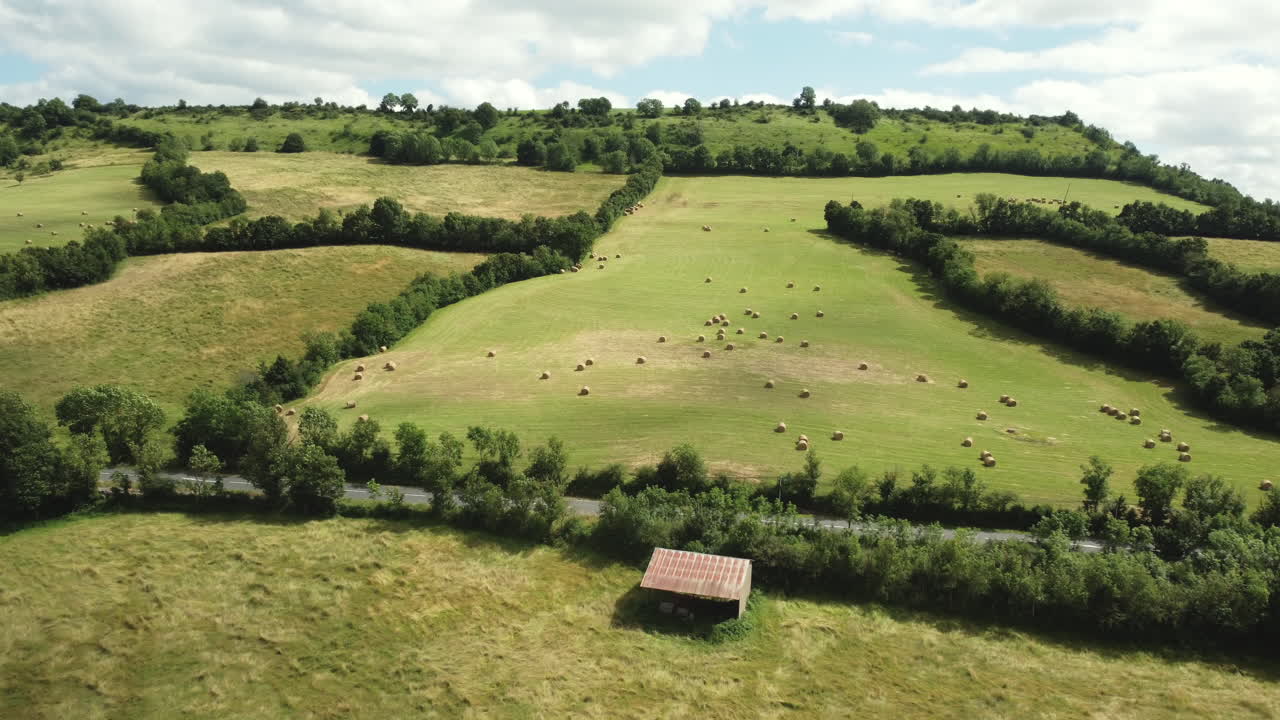 Aerial view of a rural landscape with hay bales and farm buildings