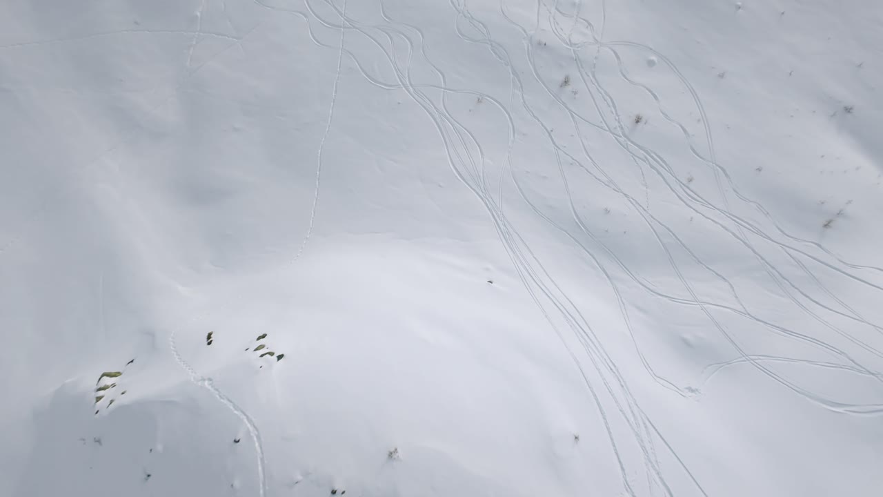 Drone FPV flying around pilot with wireless goggles, snow mountain. Aerial, copy space