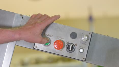 close-up shot of a hand pressing the green start button on a machine