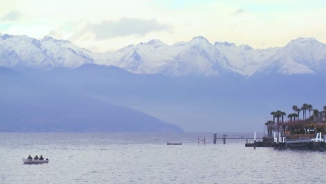 Un-Barco-De-Pesca-Flota-Ante-Un-Hermoso-Y-Pequeño-Pueblo-Italiano-De-Bellagio-A-Orillas-Del-Lago-De-Como,-Con-Los-Alpes-Italianos-En-Segundo-Plano.