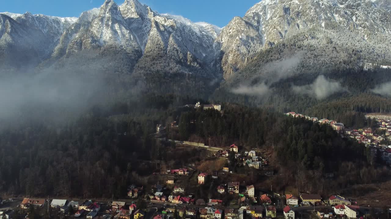 Veduta aerea di un paesino di montagna attraverso piccole nuvole