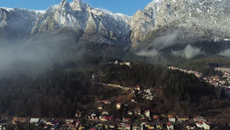 Aerial-View-Of-Small-Town-At-Mountain-Through-Small-Clouds