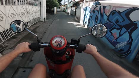 pov shot of a man driving a moped through a backalley street in chiang mai, thailand