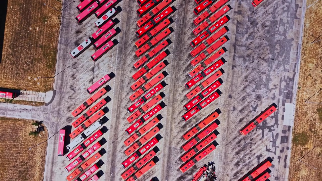 Buses parked in a large yard during daytime in a city