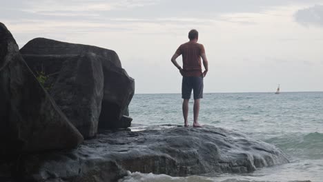 la espalda de un hombre de pie en la roca con olas estrelladas en la playa de dam trau en vietnam