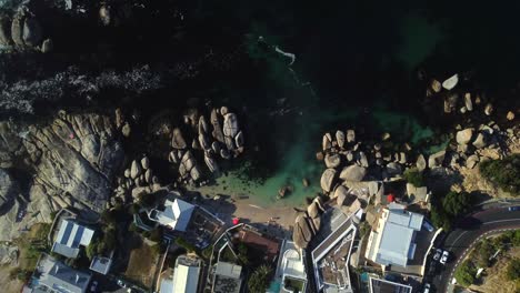 Drohnenaufnahme-Aus-Der-Vogelperspektive-Vom-Strand-Von-Bakoven-In-Camps-Bay,-Kapstadt-–-Drohne-Steigt-über-Eine-Kleine-Strandbucht-Herab