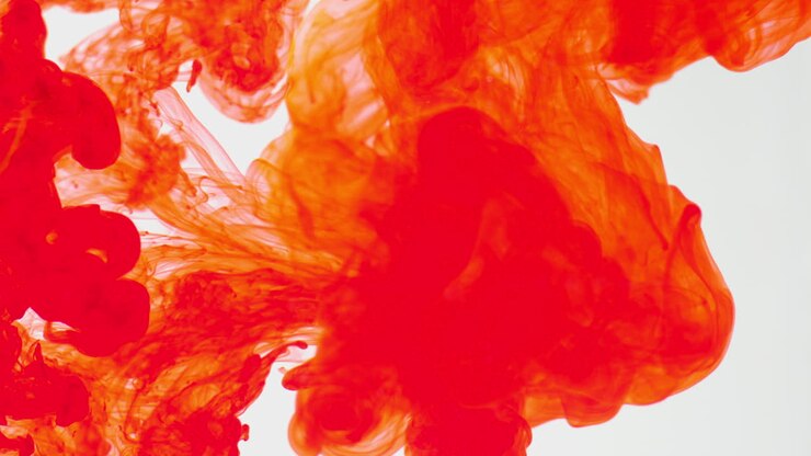 Orange Paint Or Dye Dropped Into Water Against White Background To Create Swirling Colourful Smoke Background