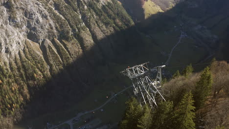 drone view overhead swiss cable car in summer descending vertical drop to village of lauterbrunnen in mountain valley