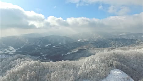 high aerial view above a snow covered winter valley surrounded by mountains