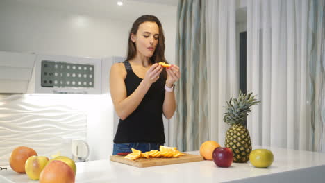 beautiful young woman eating an orange in the kitchen. healthy eating. fresh fruits. lifestyle.