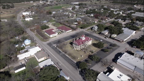 Aerial-Shot-over-Johnson-City,-Texas,-tilt-up-from-the-historic-courthouse-to-the-hill-country-horizon