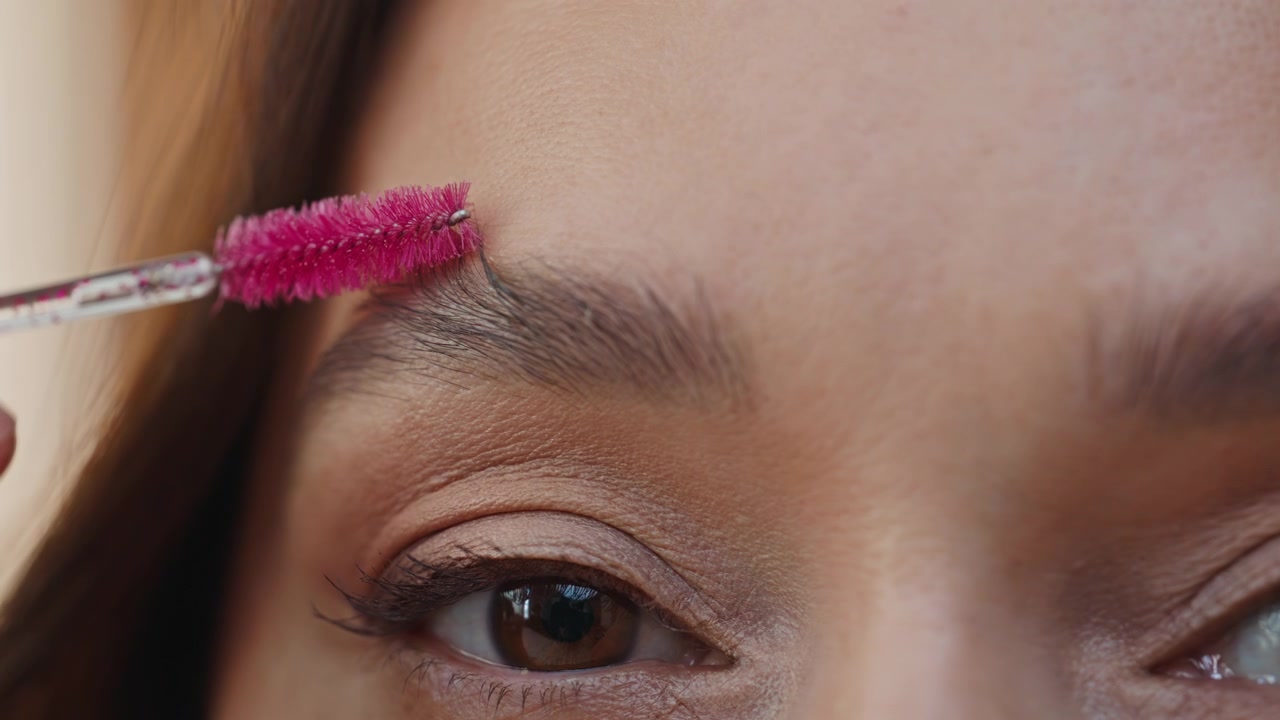 Closeup woman grooming eyebrows with makeup brush looking mirror. Lady styling