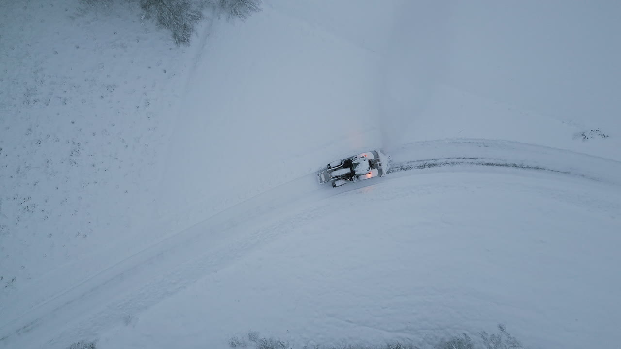 tractor de arado de nieve con luces brillantes en el paisaje de invierno, vista aérea de arriba hacia abajo