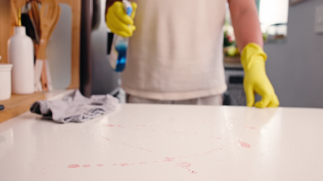 Person in Yellow Gloves Cleaning Stained Kitchen Counter