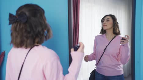 Young-woman-spraying-perfume-in-front-of-the-mirror.