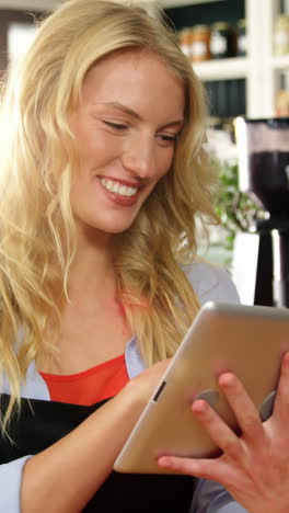 smiling waitress standing at counter using digital tablet