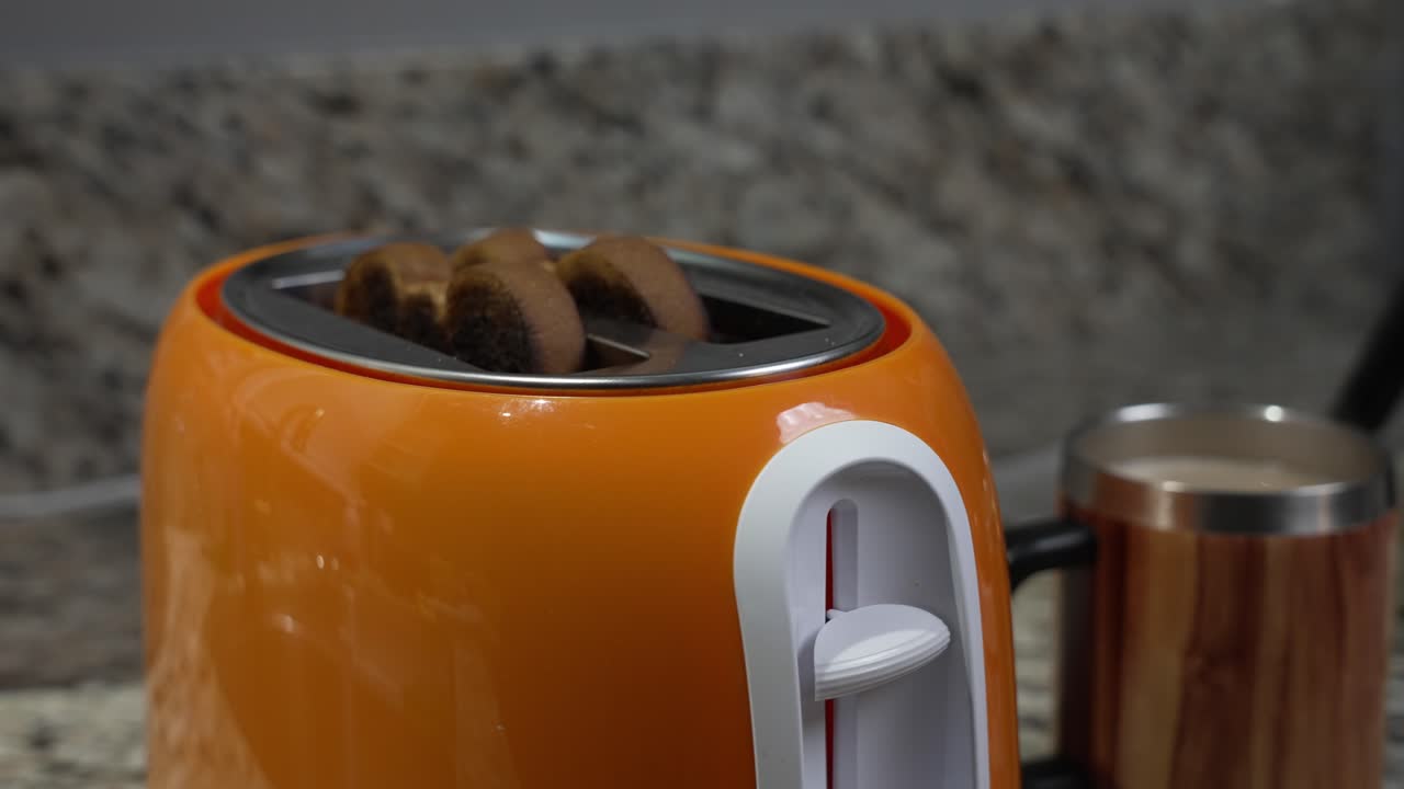 Toast pops out of an orange toaster on a marble counter