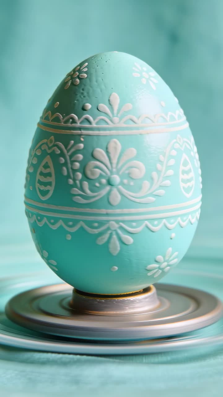 Spinning turntable rotating turquoise egg to show white bands on teal backdrop, gold collar visible