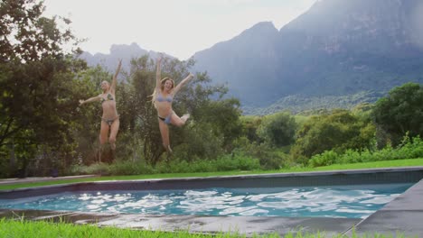 Female-friends-jumping-together-in-swimming-pool-at-resort-4k