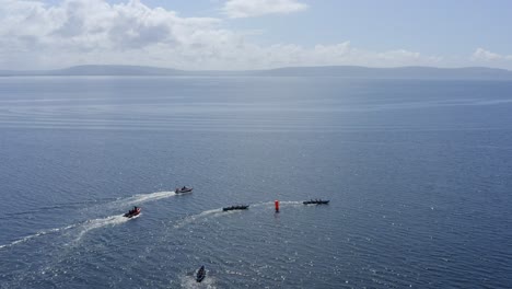 aerial high angle view looking down over currach boats racing around buoy towards county clare, ireland