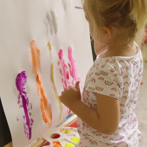 Little-girl-standing-painting-at-an-easel