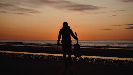 Man-running-with-guitar-in-back-sand-beach-at-sunset-5