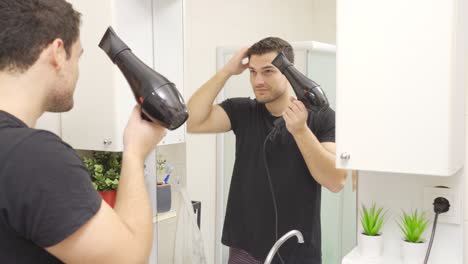 el hombre secándose el cabello con un secador.