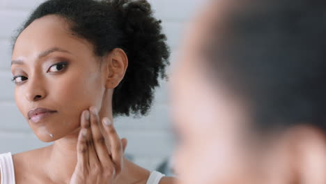 portrait beautiful african american woman looking in mirror at perfect skin enjoying natural complexion getting ready at home