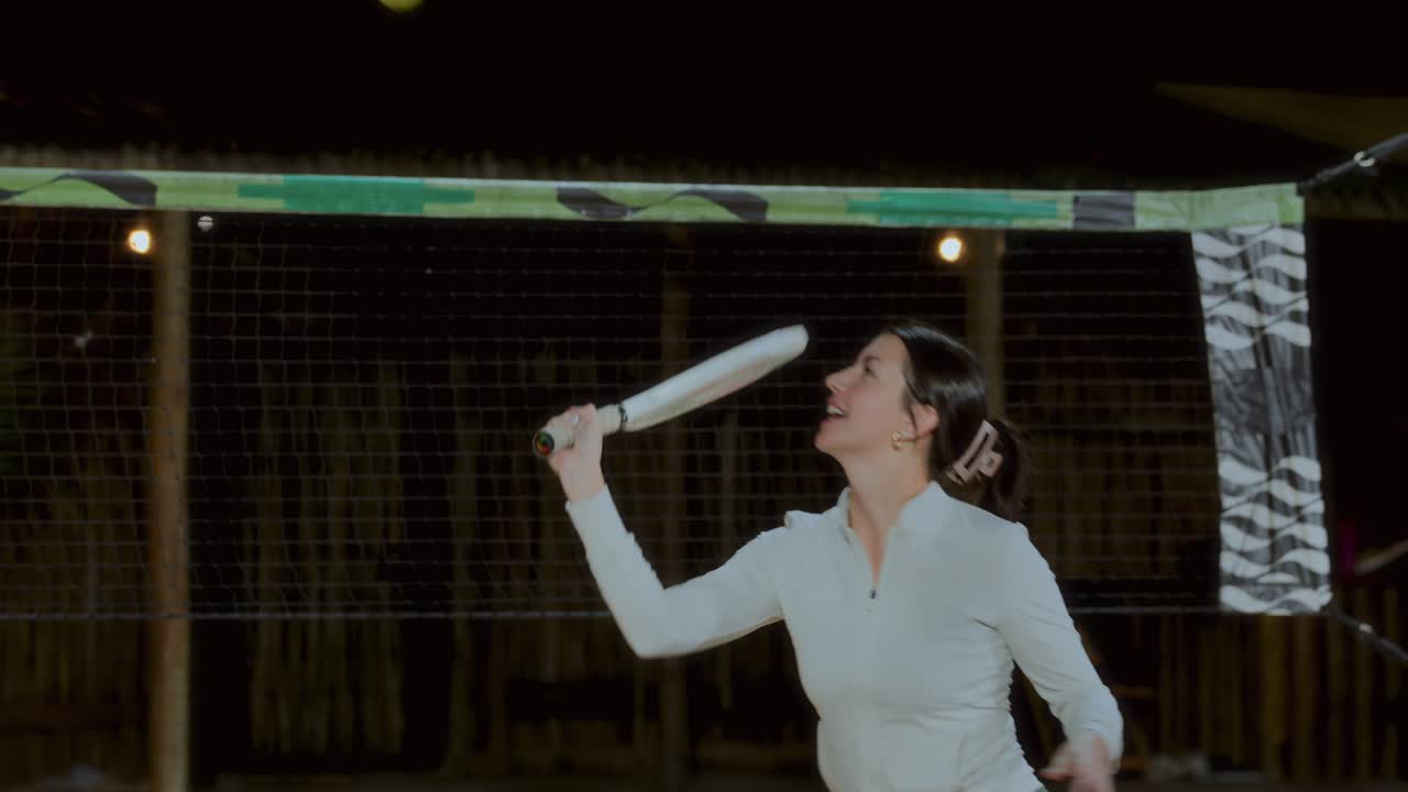 A woman playing beach tennis or paddleball at night