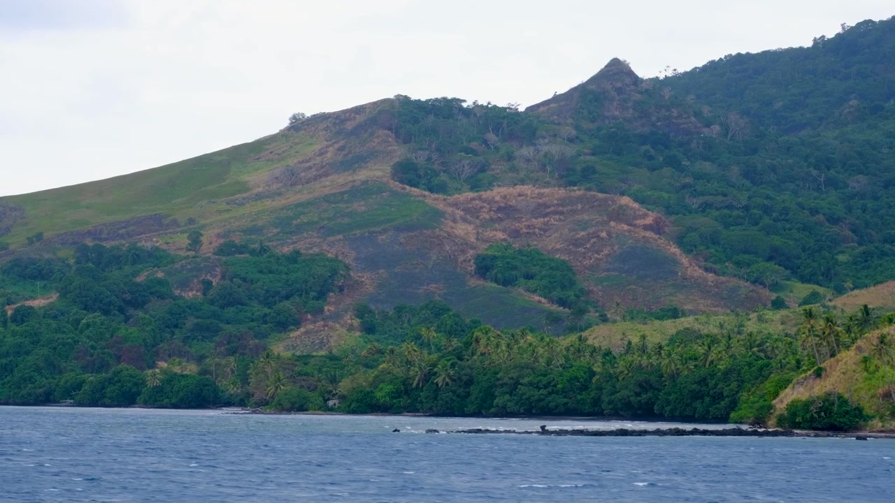 Ambiente costiero impervio dell'Isola di Ovalau, Arcipelago di Lomaiviti alle Figi, Pacifico del Sud, ripreso da un traghetto in movimento con vista sull'oceano