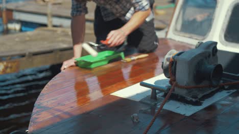 Young-man-rolling-varnish-wooden-boat-bow