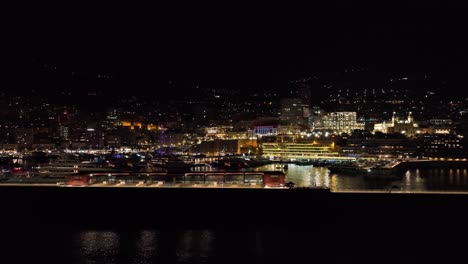 nighttime view of monaco's illuminated harbor and skyline reflecting on the water.