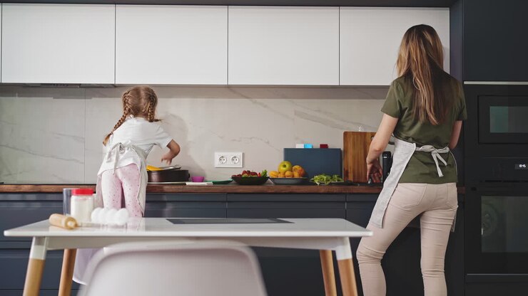 madre con piccola figlia cucina la cena in una cucina moderna