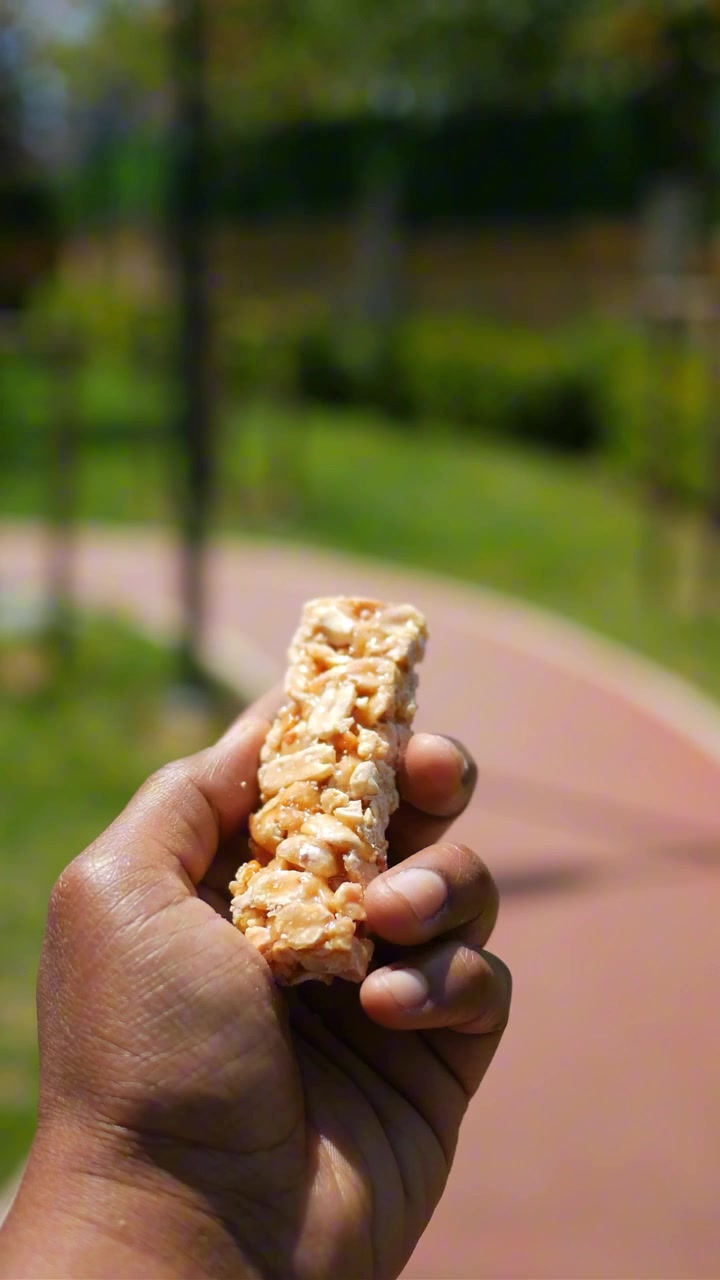 Hand Holding a Nut and Grain Energy Bar Outdoors