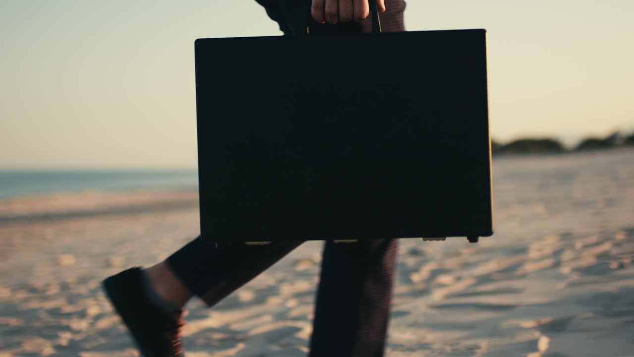 해가 지는 해변에서 브리프케이스를 들고 있는 사업가