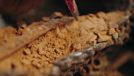 close up of brush removing clay from welded iron detail