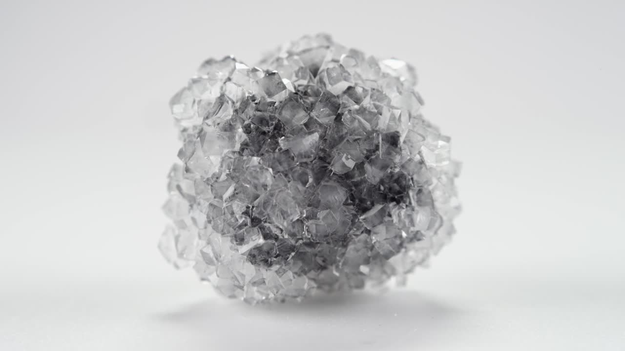 어두운 중심을 가진 보락스 결정은 밝은 배경에 대해 무한 루프로 회전합니다.