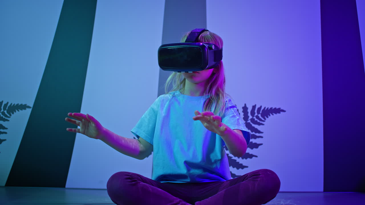 Girl child in VR glasses having interaction with virtual reality, low angle shot