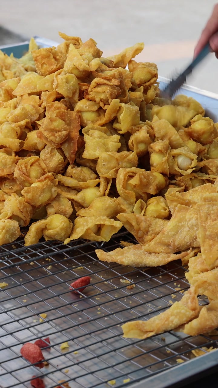 Ambulante che confeziona wonton fritti croccanti in una bancarella di street food