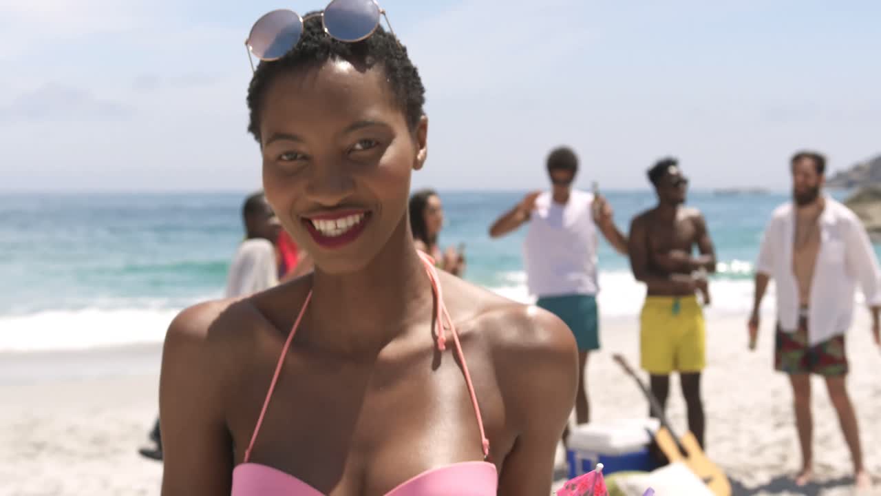 Vista frontale di donna afroamericana che manda un bacio volante e balla sulla spiaggia 4k