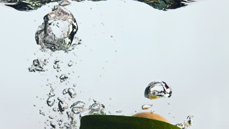 medio aguacate cae agua en súper cámara lenta de cerca. vegetal caído bajo el agua