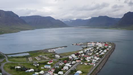 aerial backwards shot flateyri town at westfjord with mountain range in background, iceland