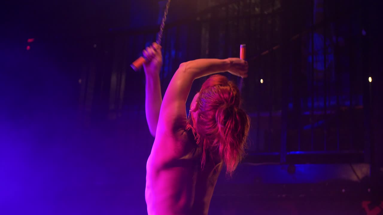 Dançarina do fogo sensual gira bastões de fogo ao redor da cabeça no palco