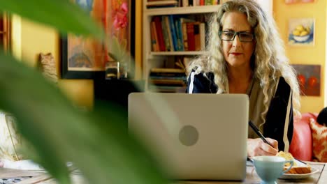 mujer madura usando tableta gráfica en casa 4k