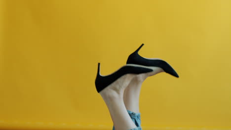 woman's legs in high heels against yellow background