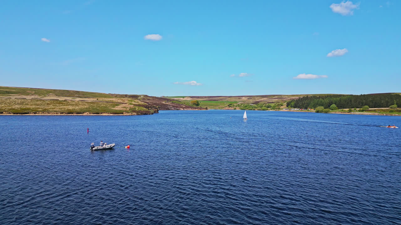 아름다운 요크셔 시골에 자리 잡은 윈스카르 저수지,  ⁇  세일을 가진 작은 1인 보트가 숨막히는 파란 호수에서 흥미진진한 보트 경주에 참여하는 동안