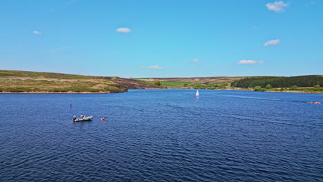 Winscar-Reservoir,-Eingebettet-In-Die-Malerische-Landschaft-Von-Yorkshire,-Während-Kleine-Einmannboote-Mit-Weißen-Segeln-An-Einem-Spannenden-Bootsrennen-Auf-Dem-Atemberaubenden-Blauen-See-Teilnehmen