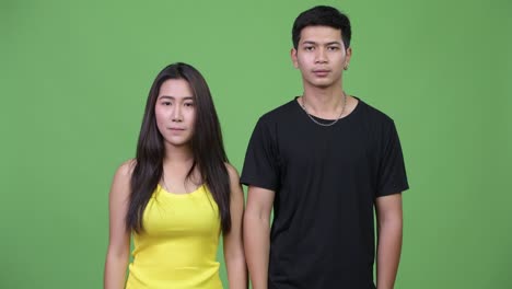 young asian couple pointing up together