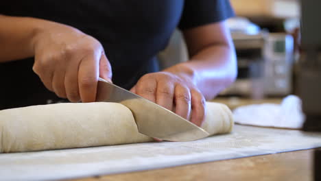 slicing raw dough roll into cinnamon rolls for baking - isolated slow motion