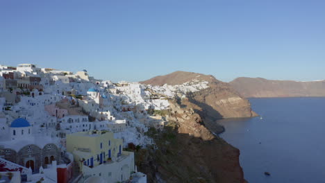 Aerial:-Flying-over-Oia-in-Santorini-at-low-altitude-during-sunset